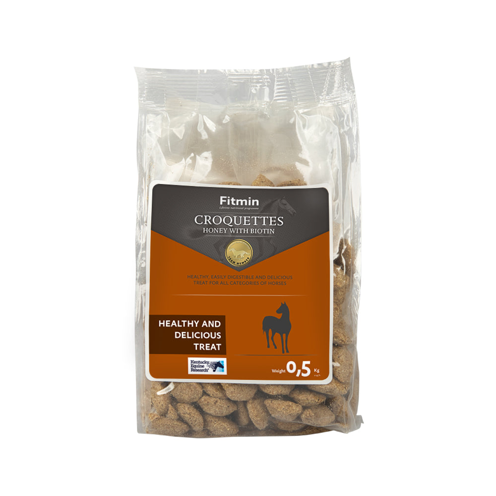 A 0.5kg clear plastic bag of Fitmin Horse Croquettes with honey and biotin. The label highlights these as a healthy and delicious reward, specifically formulated to provide a tasty treat while supporting the horse's general well-being.