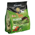 A side-angled view of a green and black stand-up pouch of Fitmin Horse Snax. The packaging features silhouettes of horses and illustrations of natural ingredients including apples, carrots, rosehips, and chamomile. Labeled as a "Super Premium Horse Snack," it includes the Fitmin Faktor and contains visible compressed herbal snack balls through a transparent side panel.
